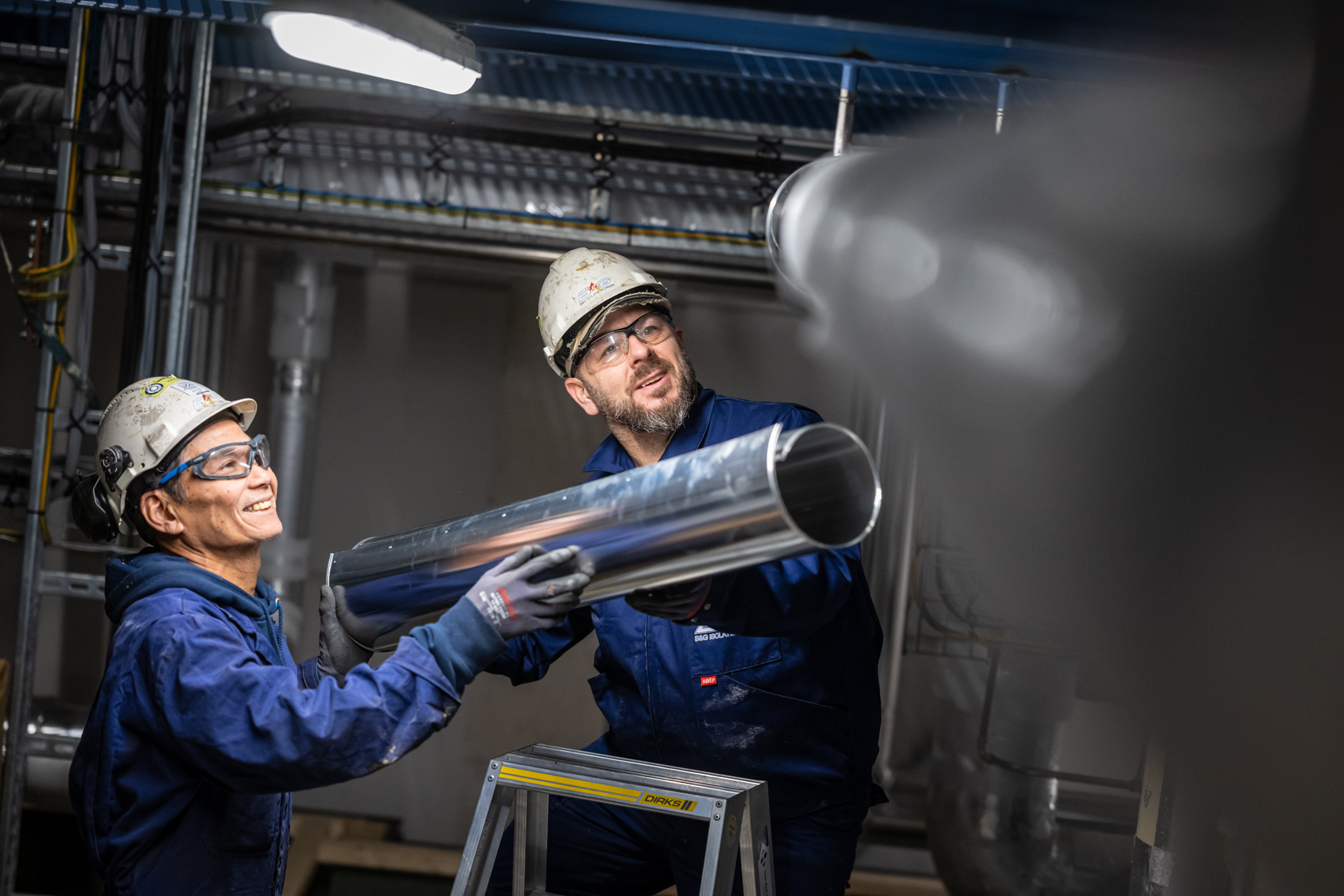 Monteurs installeren metalen leiding in fabriekshal
