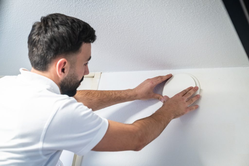 Man installeert rookmelder aan plafond