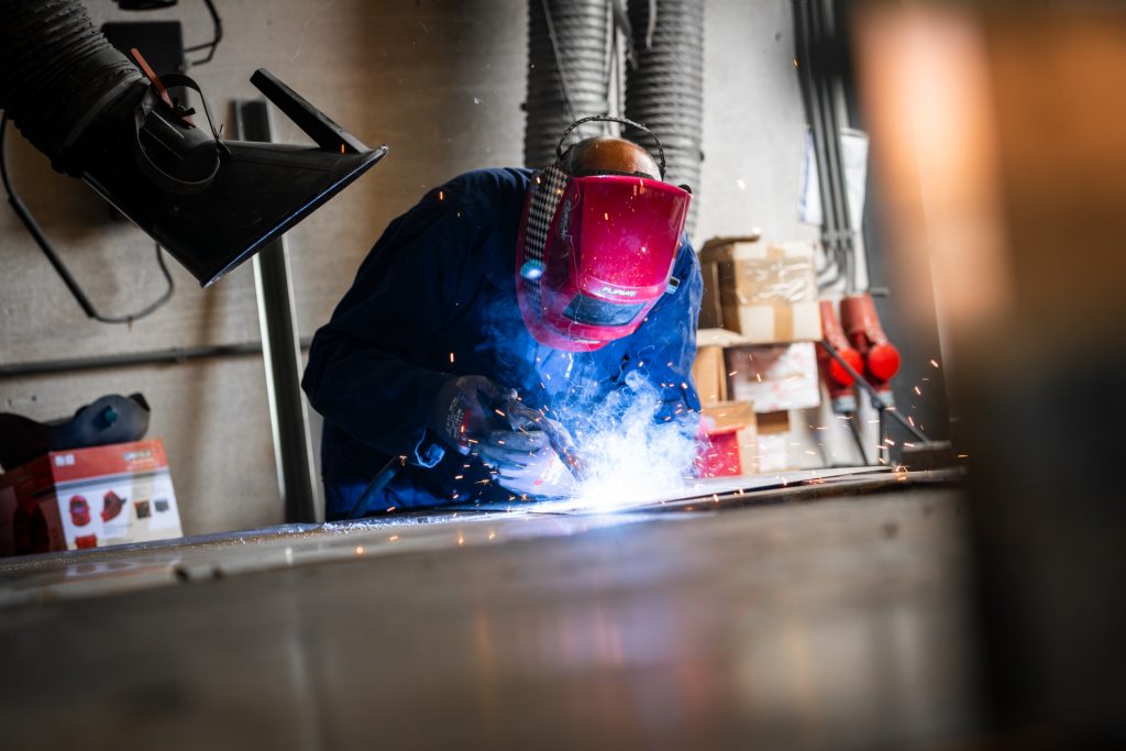 Lasser met helm, vonken en rook zichtbaar