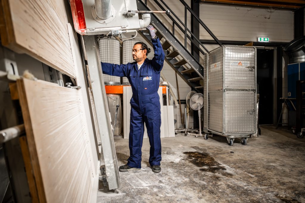 Man in overall werkt aan fabriekmachine