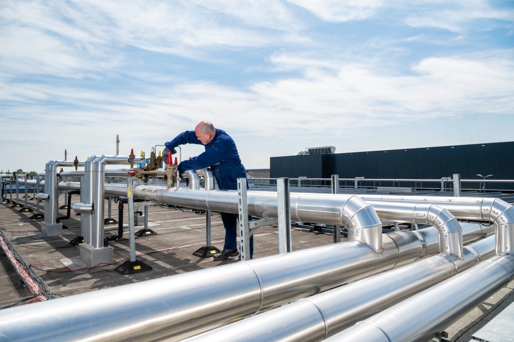 Man werkt aan industriële pijpleidingen op dak.