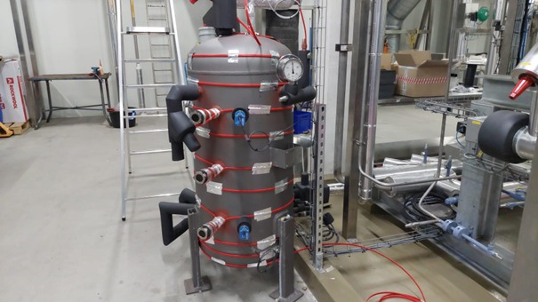 Industriële machine met leidingen en meters in fabriekshal.